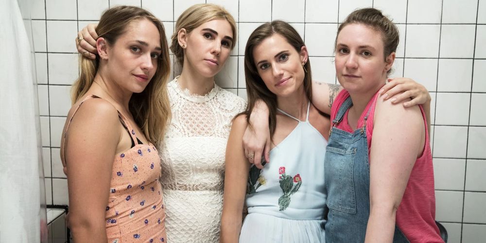 The cast of Girls pose against a white tile wall