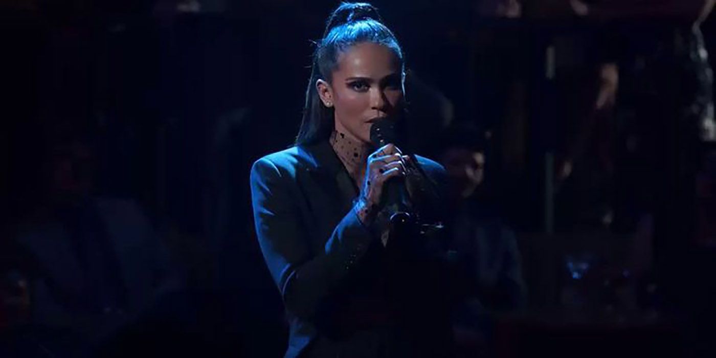 Maze from Lucifer on a dark background, mic in her hand singing.