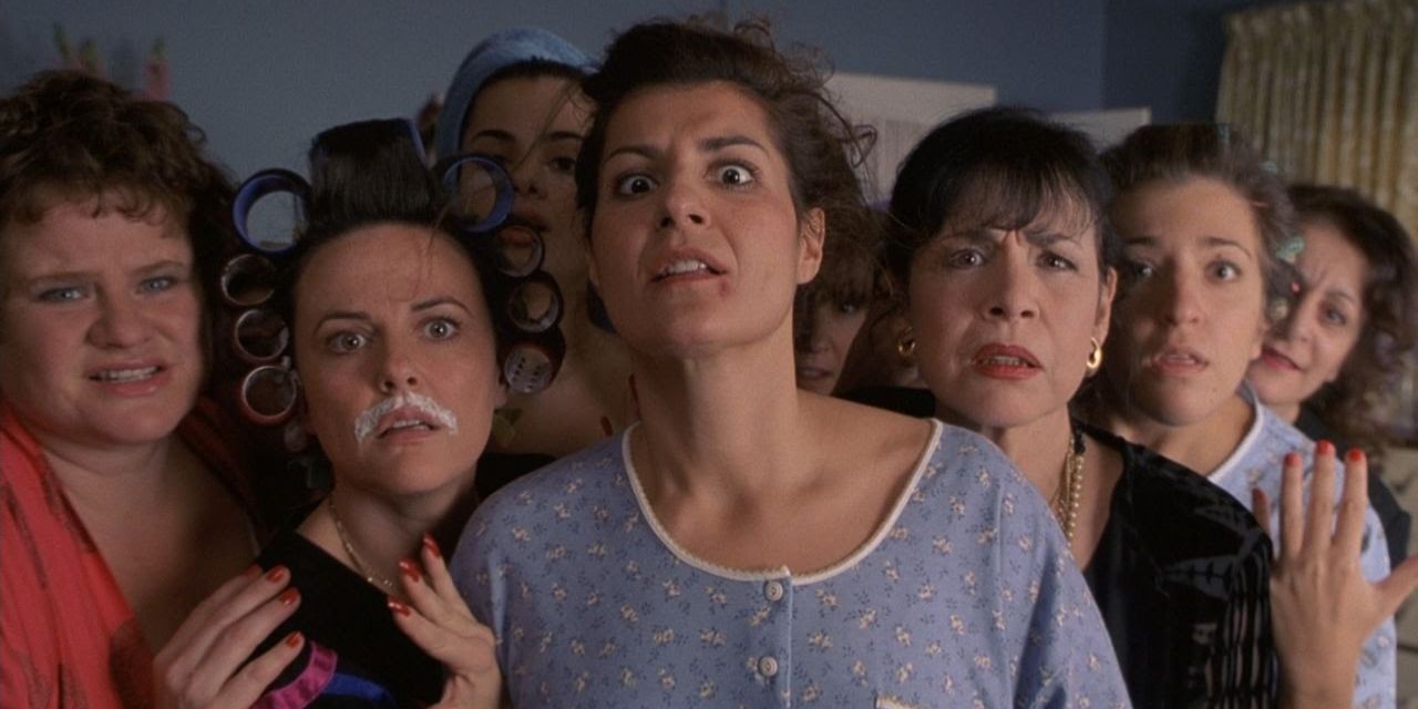 Toula examines a zit with her family behind her in My Big Fat Greek Wedding.