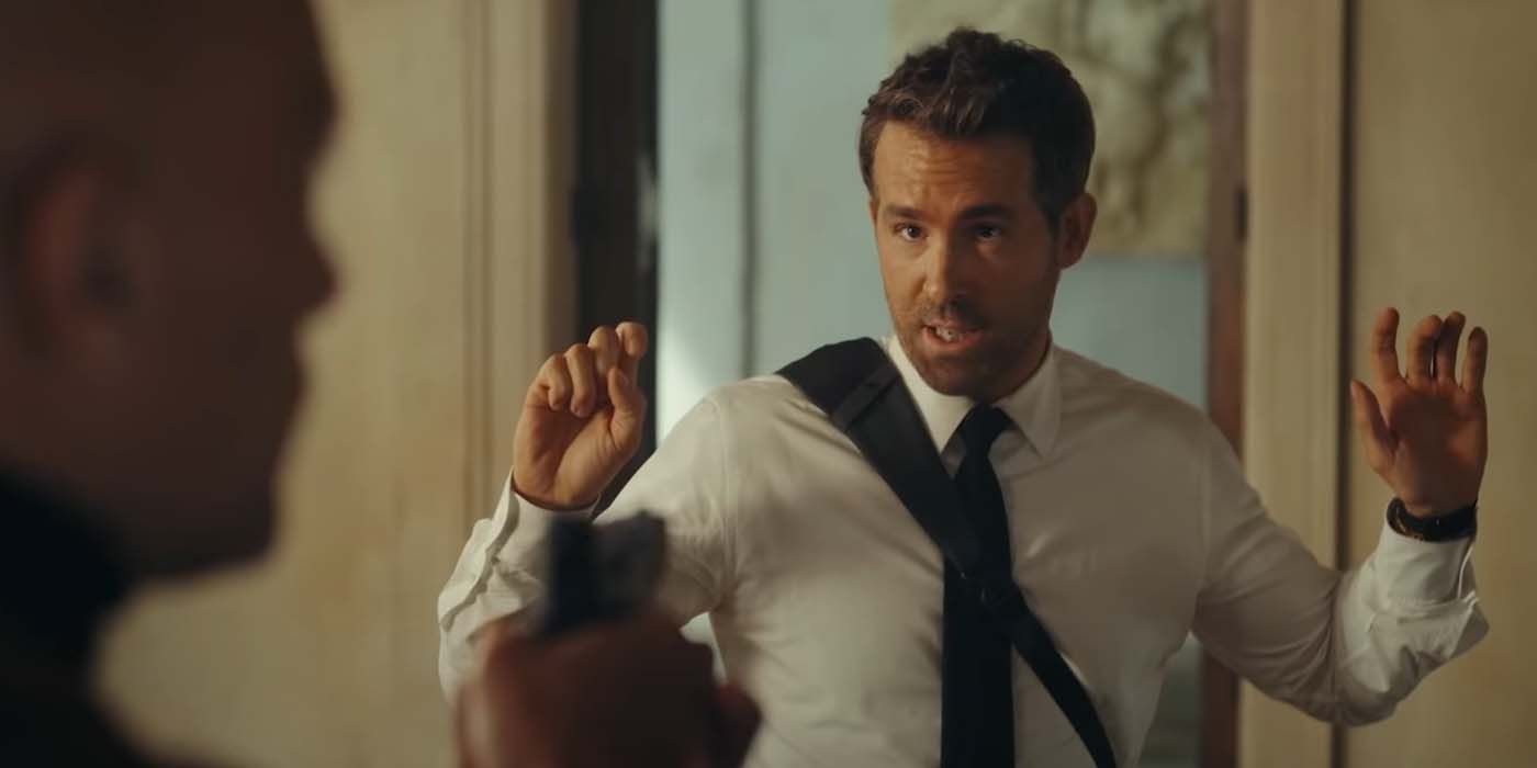Ryan Reynolds avec ses mains sous la menace d'une arme dans Red Notice