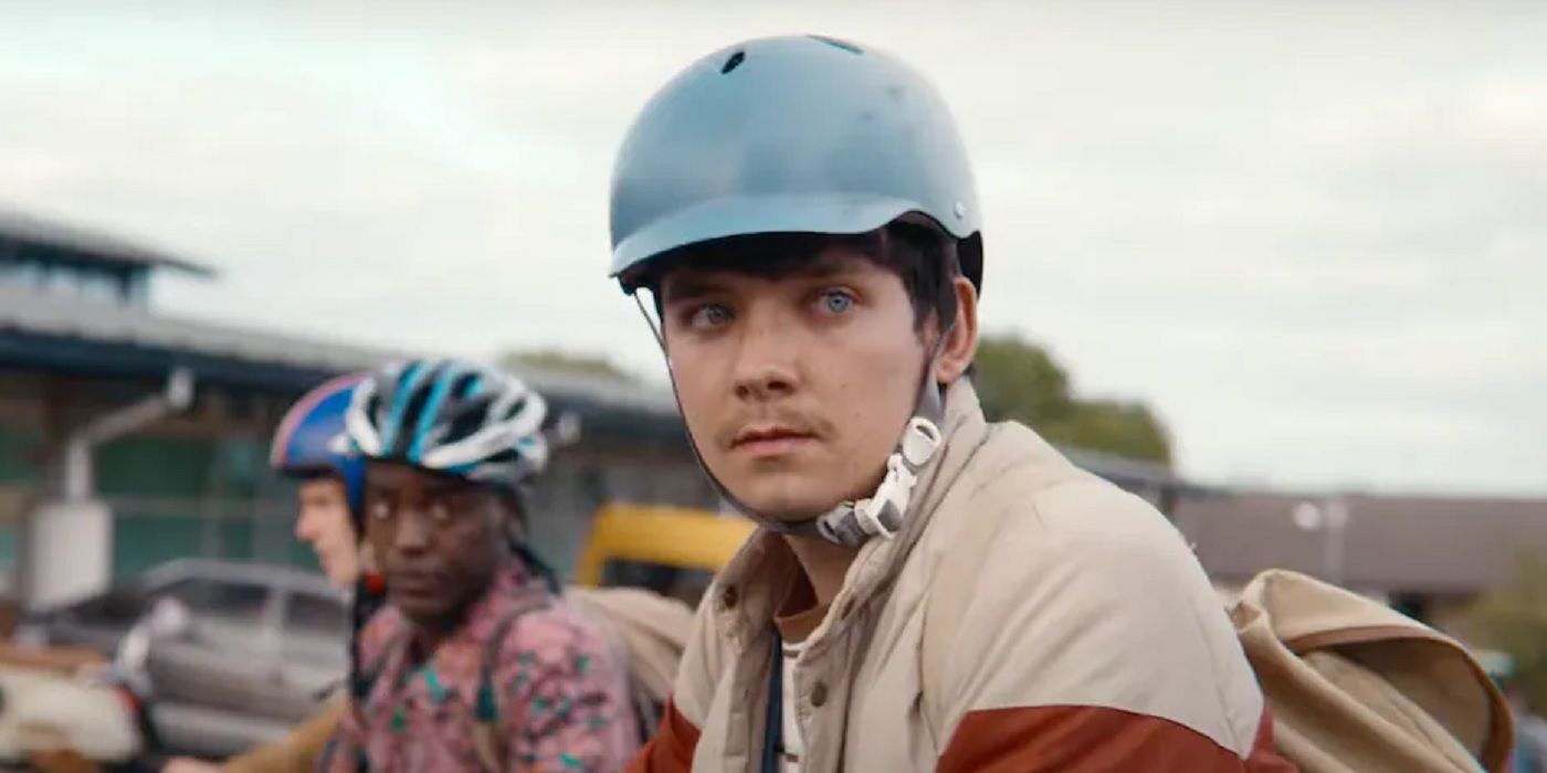 Otis with his bike helmet looking at someone in Sex Education