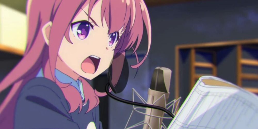 the main character of Girlish Number speaking into a recording microphone and holding a script