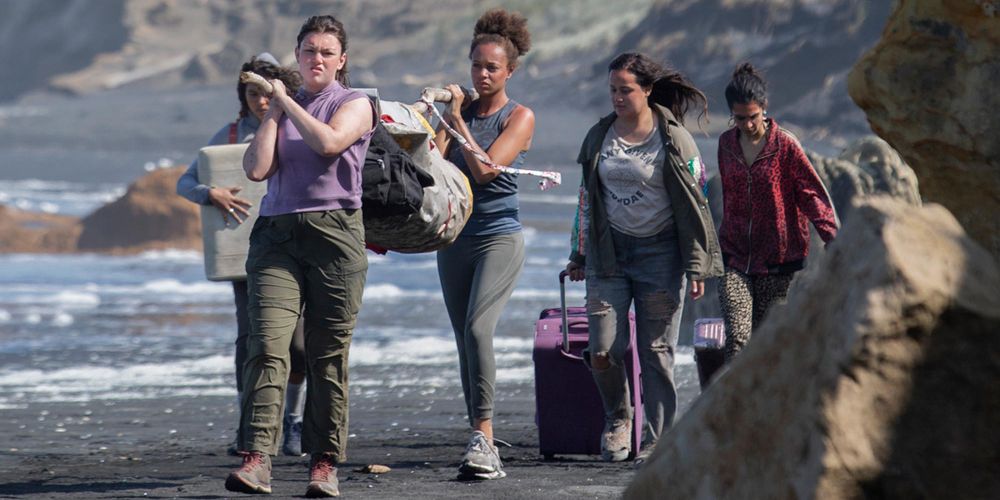 The women carry supplies on the shore on The Wilds