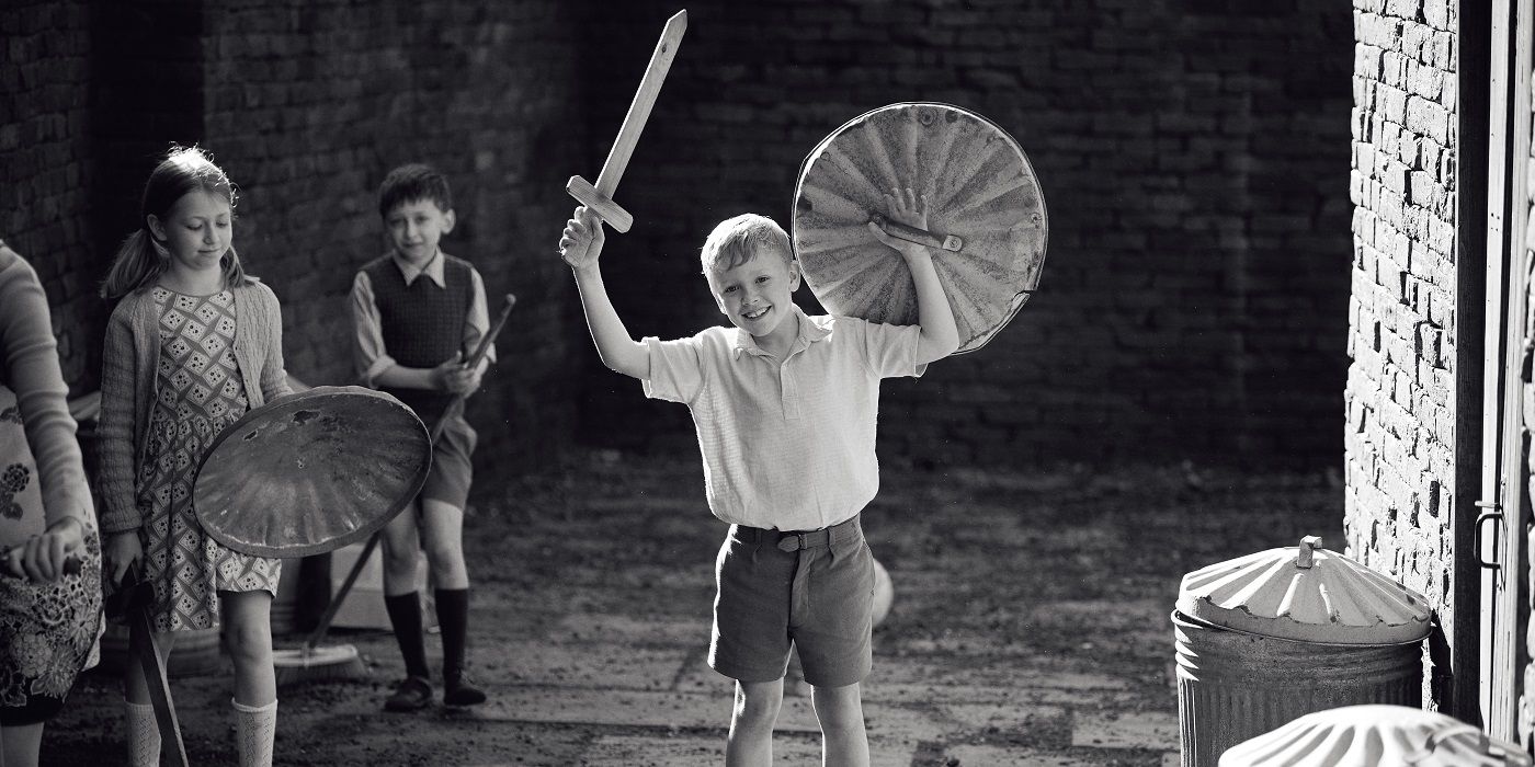 Jude Hill holds up a fake sword and shield among other children in Belfast (2021)