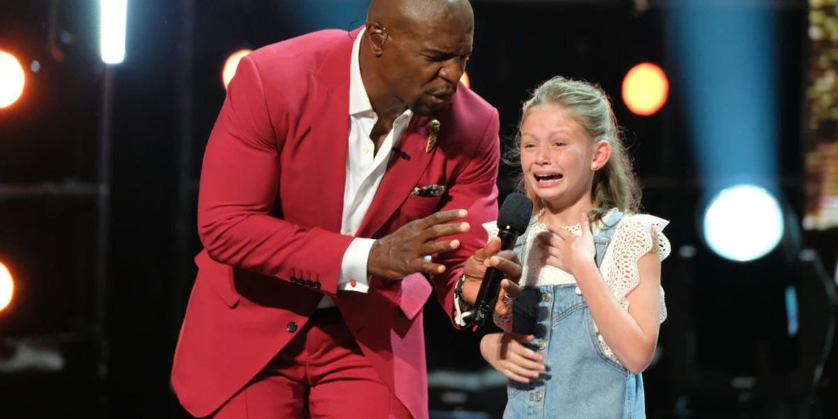 Terry Crews in a red blazer standing next to Ansley Burns on America's Got Talent