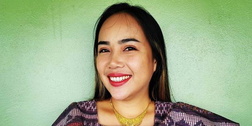 Annie Suwan From 90 Day Fiancé smiling in traditional dress against green wall