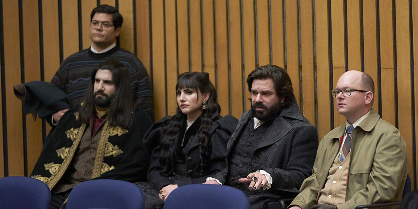 Guillermo, Nandor, Nadja, Laszlo, and Colin sitting on blue chairs in the City Council in What We Do In The Shadows.