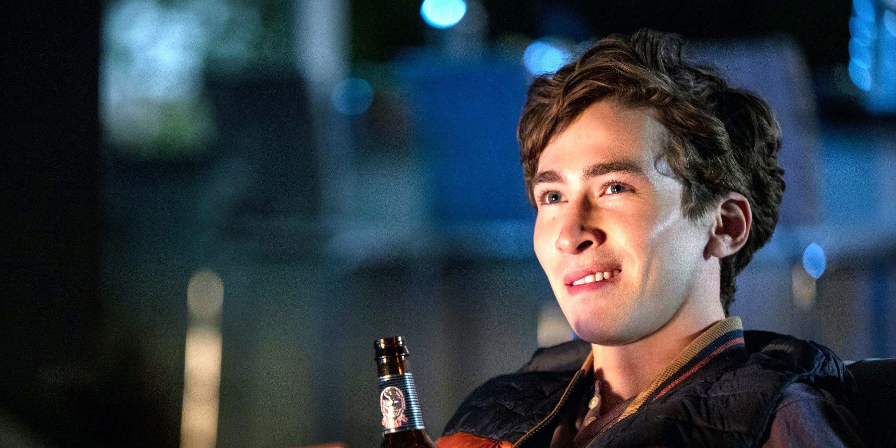 Theo Engler sosteniendo una cerveza y sonriendo en You Season 3