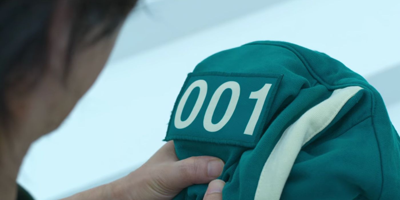 Gi-hun holding Il-nam's jacket with number 001 in Squid Game,