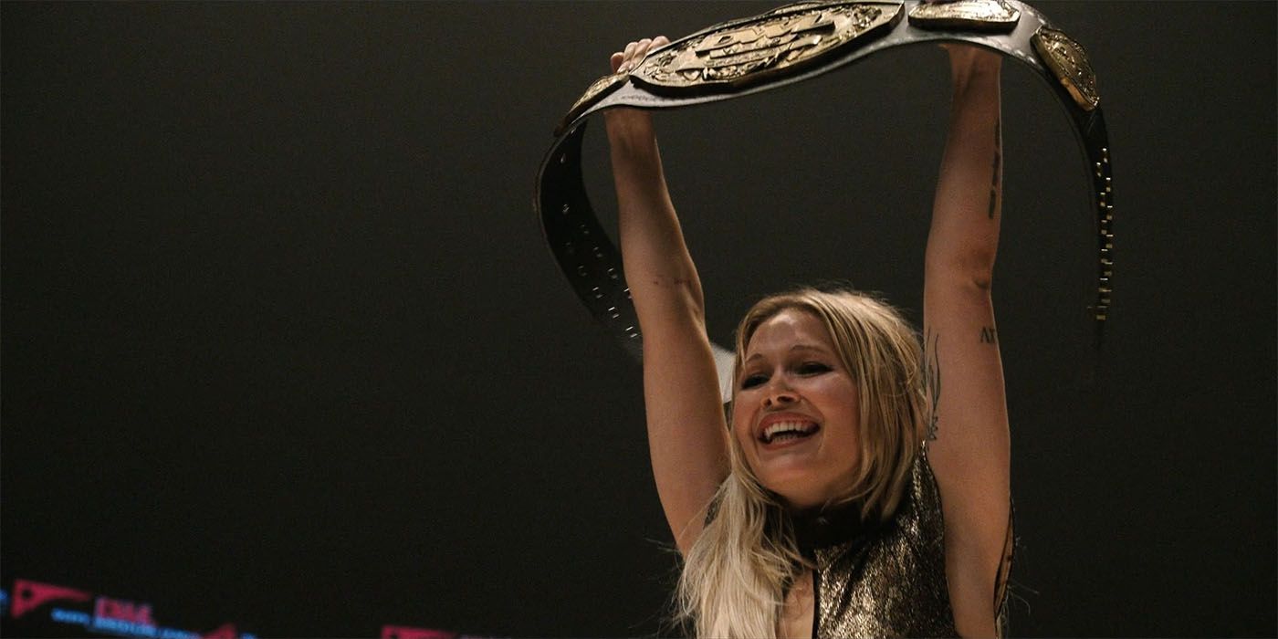 Kelli Berglund as Crystal, smiling, in the Heels season 1 finale holding a belt above her head
