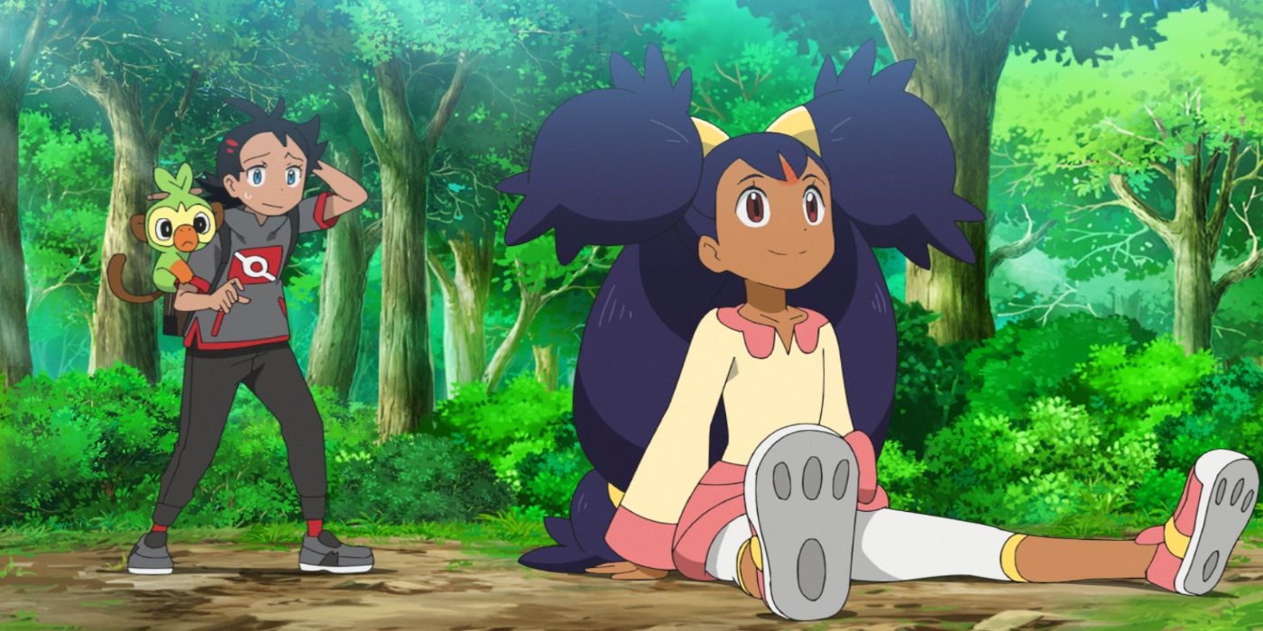Iris sitting on the ground in front of her friend in Pokemon anime