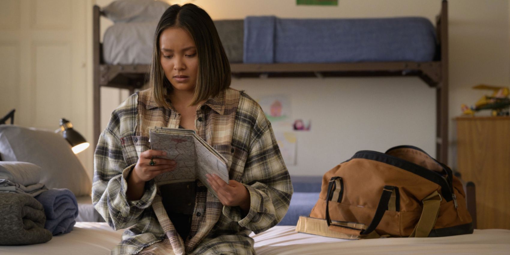 Jennie sits on a bed and examines a map in Stargirl