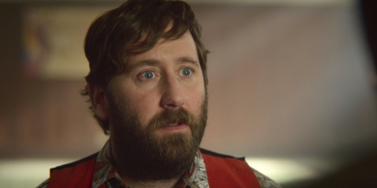 Jim Howick in Sex Education wearing a red sleeveless jacket