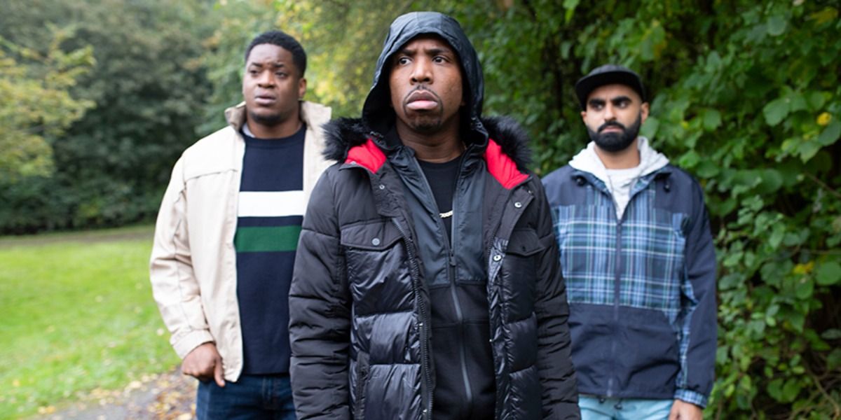 Kiell Smith-Bynoe in Man Like Mobeen, wearing a puffer jacket, two men stand behind him