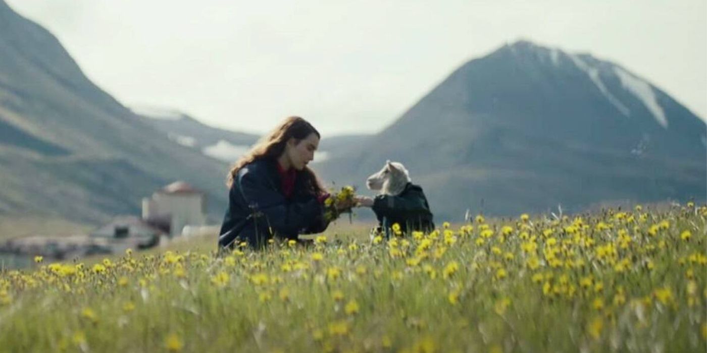 Maria sits with Ada, a lamb, in a field of flowers in Lamb.