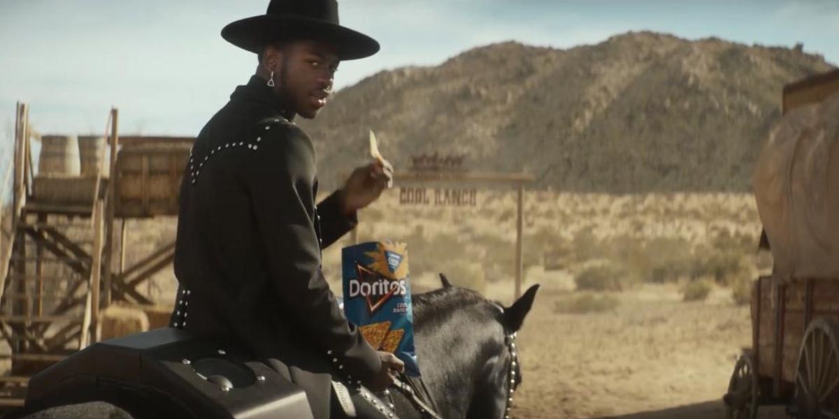 Lil Nas X eats Doritos while riding a horse in a commercial.