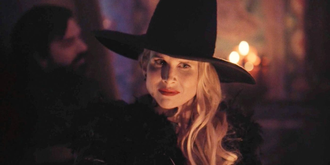 Lilith usando um chapéu de bruxa com Laszlo ao fundo em O que fazemos nas sombras.