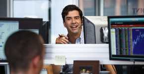 Hamish Linklater (Porter Collins) behind a computer monitor, smiling in The Big Short