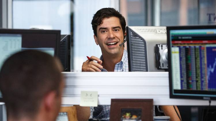 Hamish Linklater (Porter Collins) behind a computer monitor, smiling in The Big Short