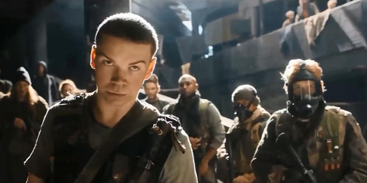 A teenge boy stands next to armored guards in Maze Runner: The Death Cure.
