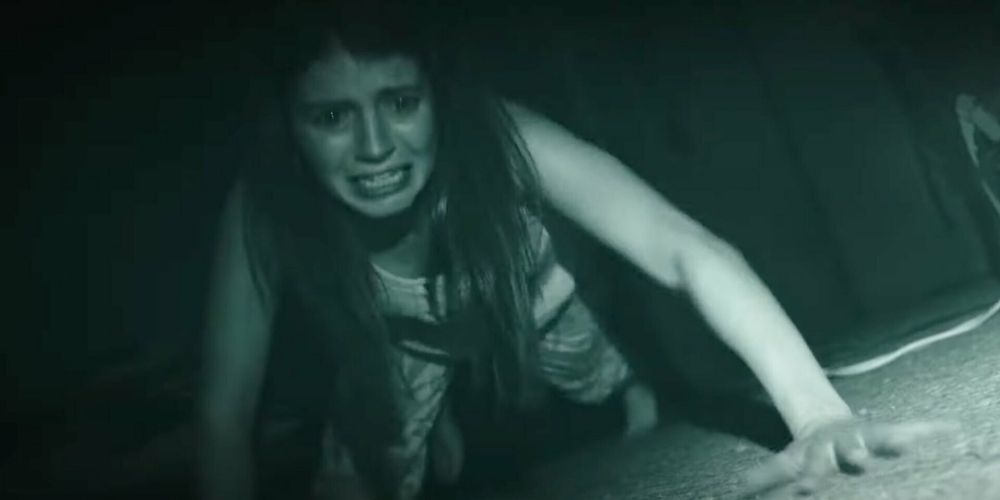 An entity bumps around a dark room, leaving Emily Bader as Margot frightened in Paranormal Activity: Next of Kin