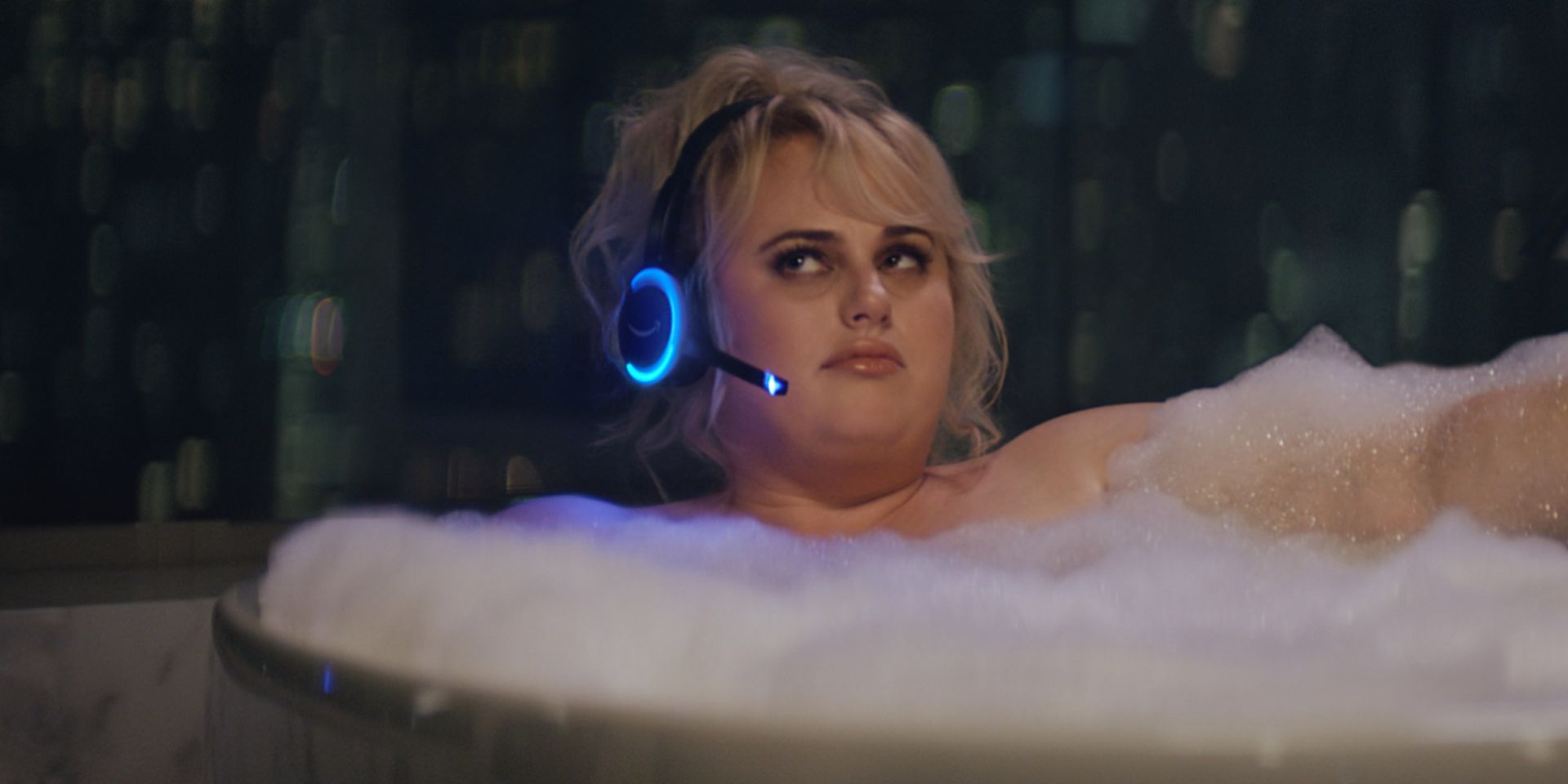 Rebel Wilson sits in a bathtub with a headset in an Alexa commercial.