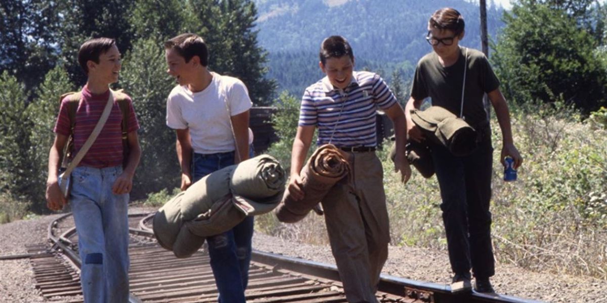 Four boys laugh and walk on railroad tracks in Stand by Me.