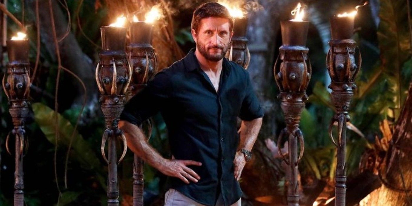 The host of Survivor Australia stands in front of a display of torches