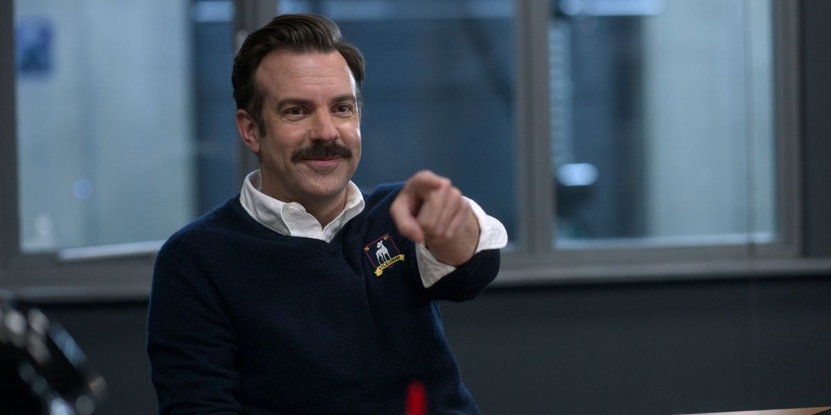 Ted pointing at someone and smiling in Ted Lasso