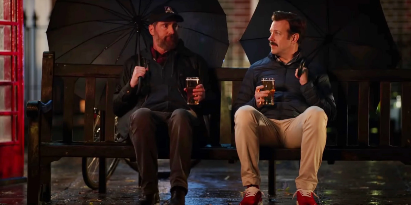 Ted Lasso and Coach Beard have drinks on a bench