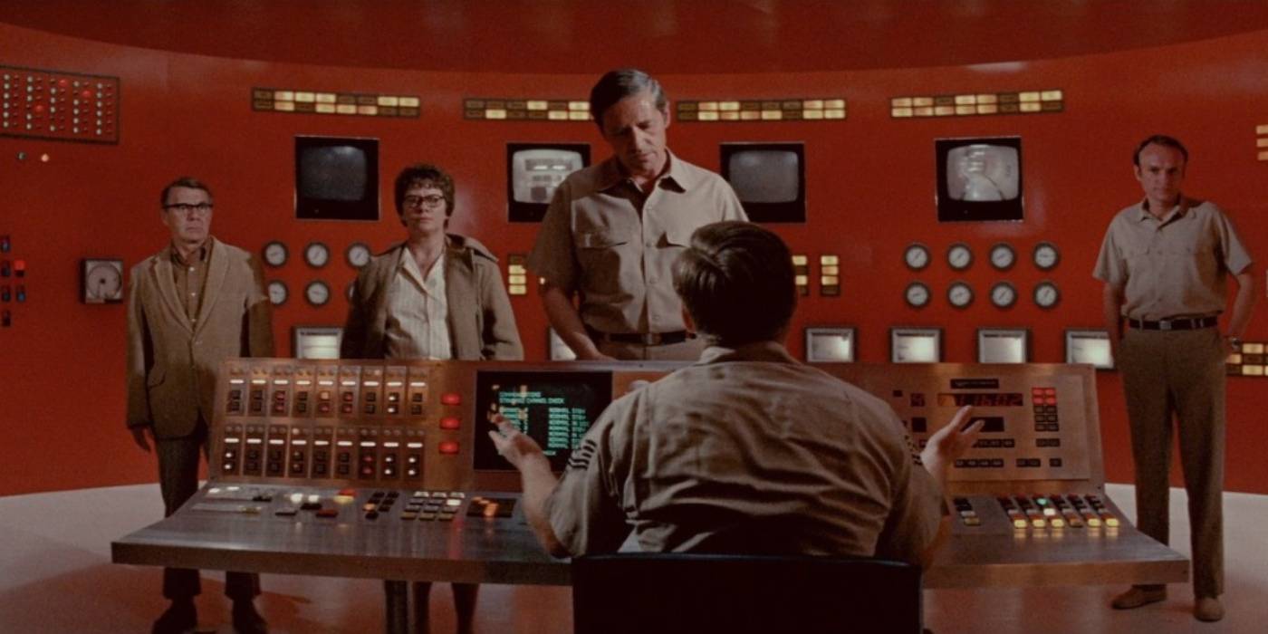 Um homem olha para um grupo de pessoas em uma sala de controle em The Andrômeda Strain.