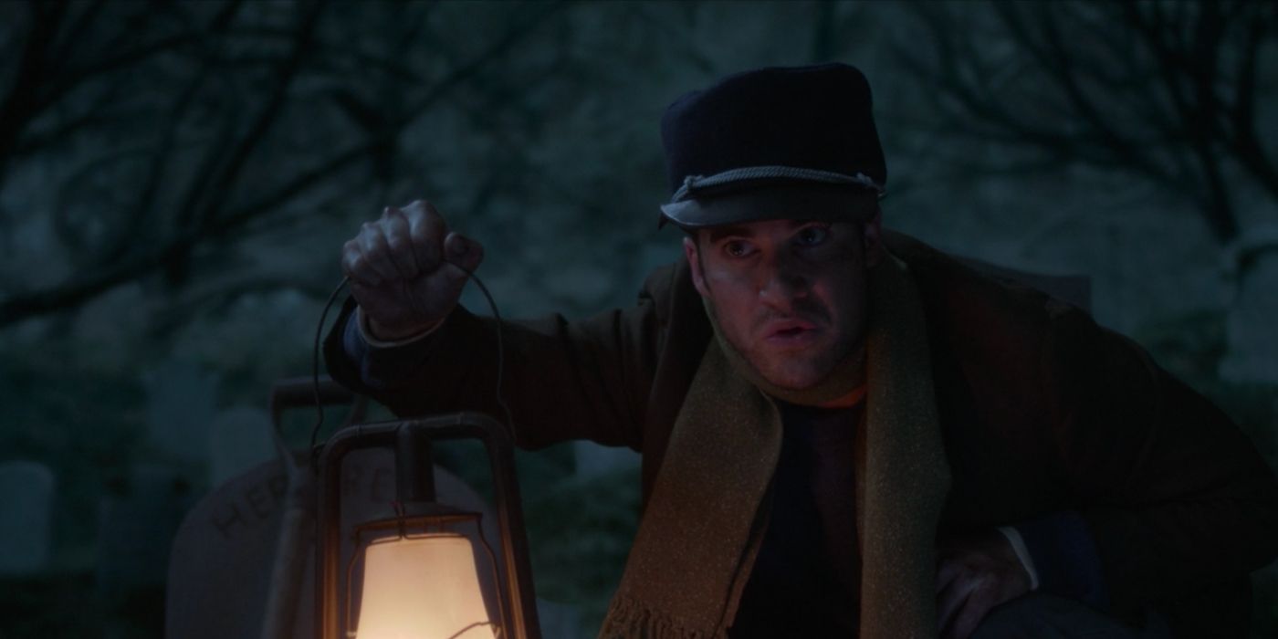 The Caretaker holds a lantern in the graveyard in Muppets Haunted Mansion