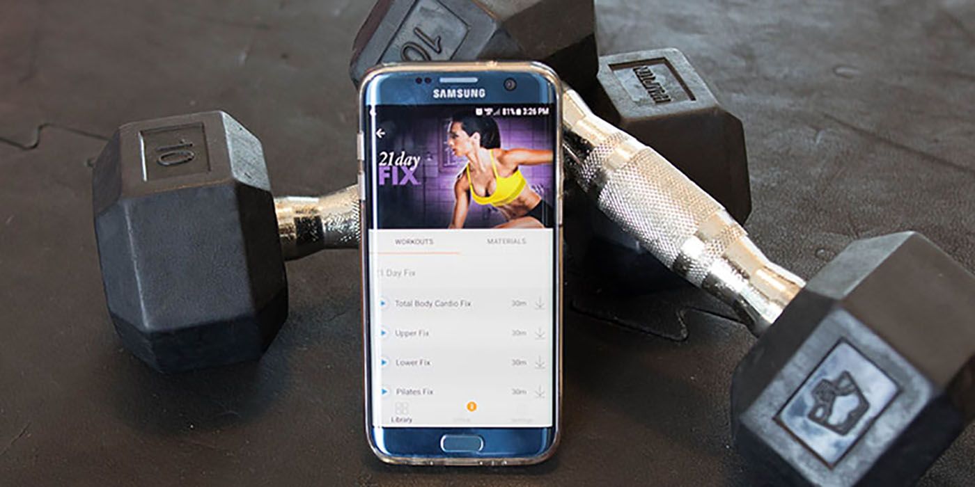 A phone with the BeachBodyOnDemand app on the screen, dumbbells behind it.