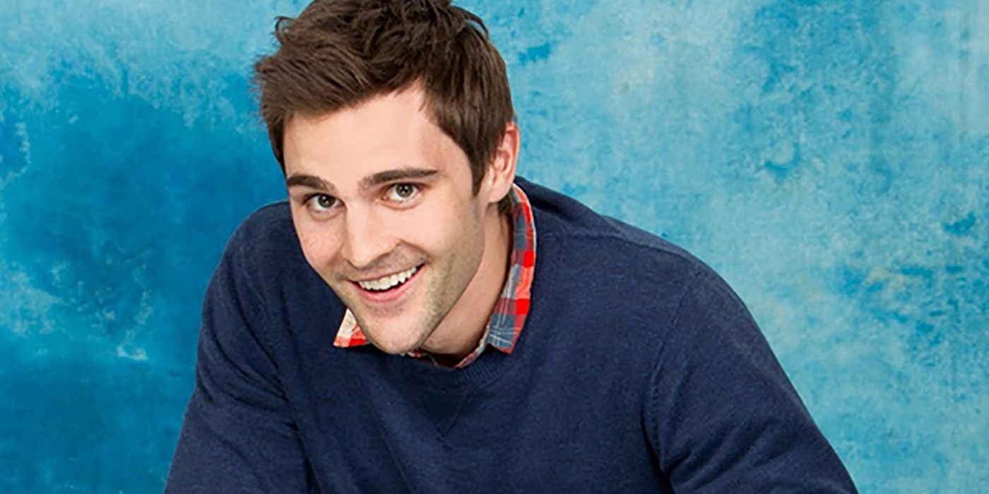 Promo pic of Nick has from Big Brother, smiling with a blue background.