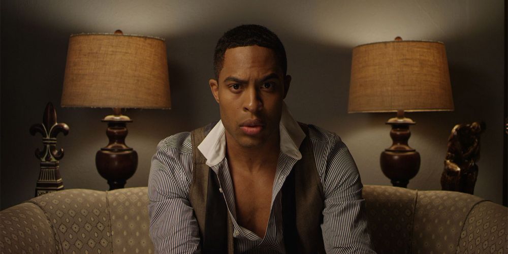 Troy sits on the sofa with shirt undone in Dear White People