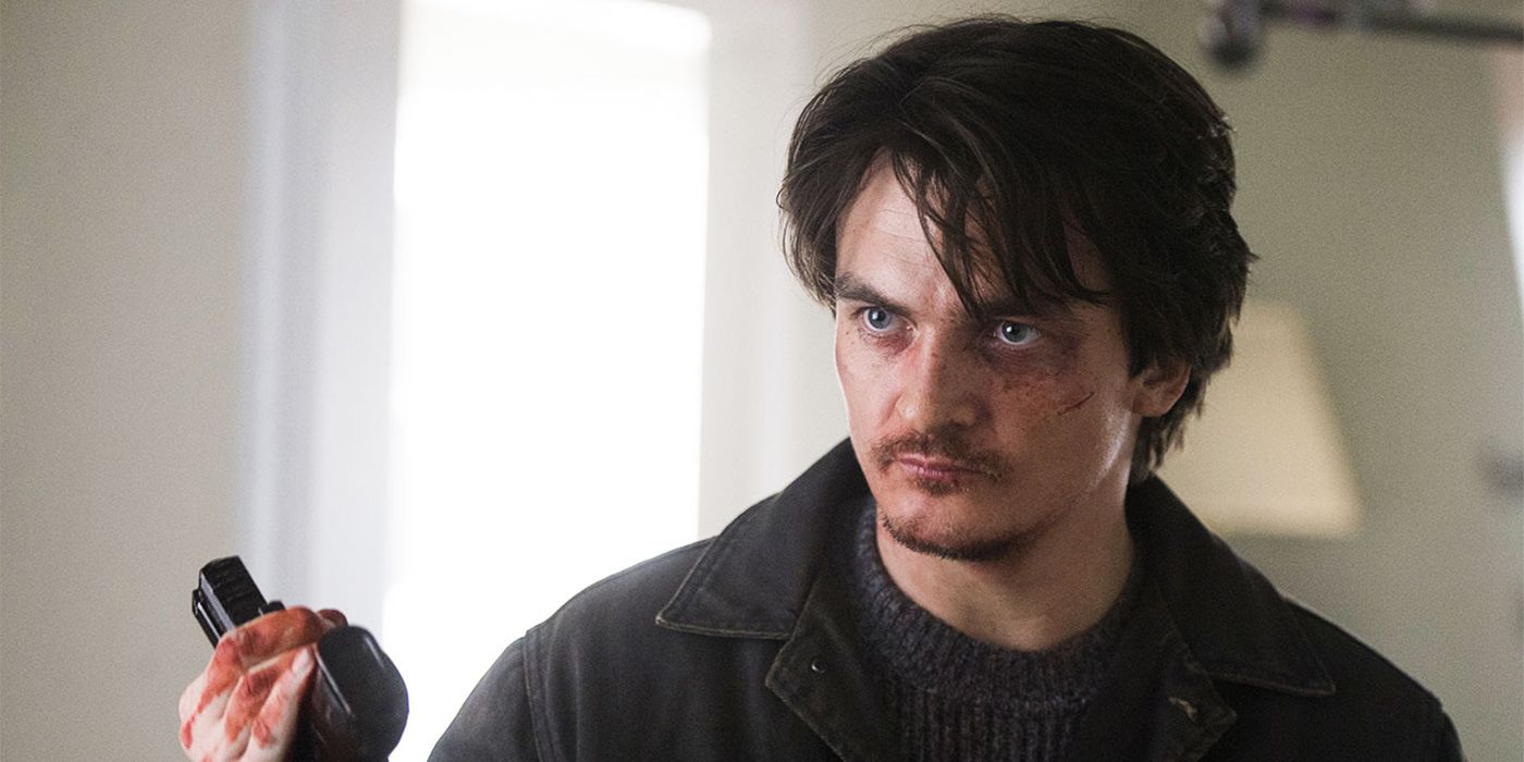 Peter Quinn from Homeland, looking disheveled and bloody, holding a gun.