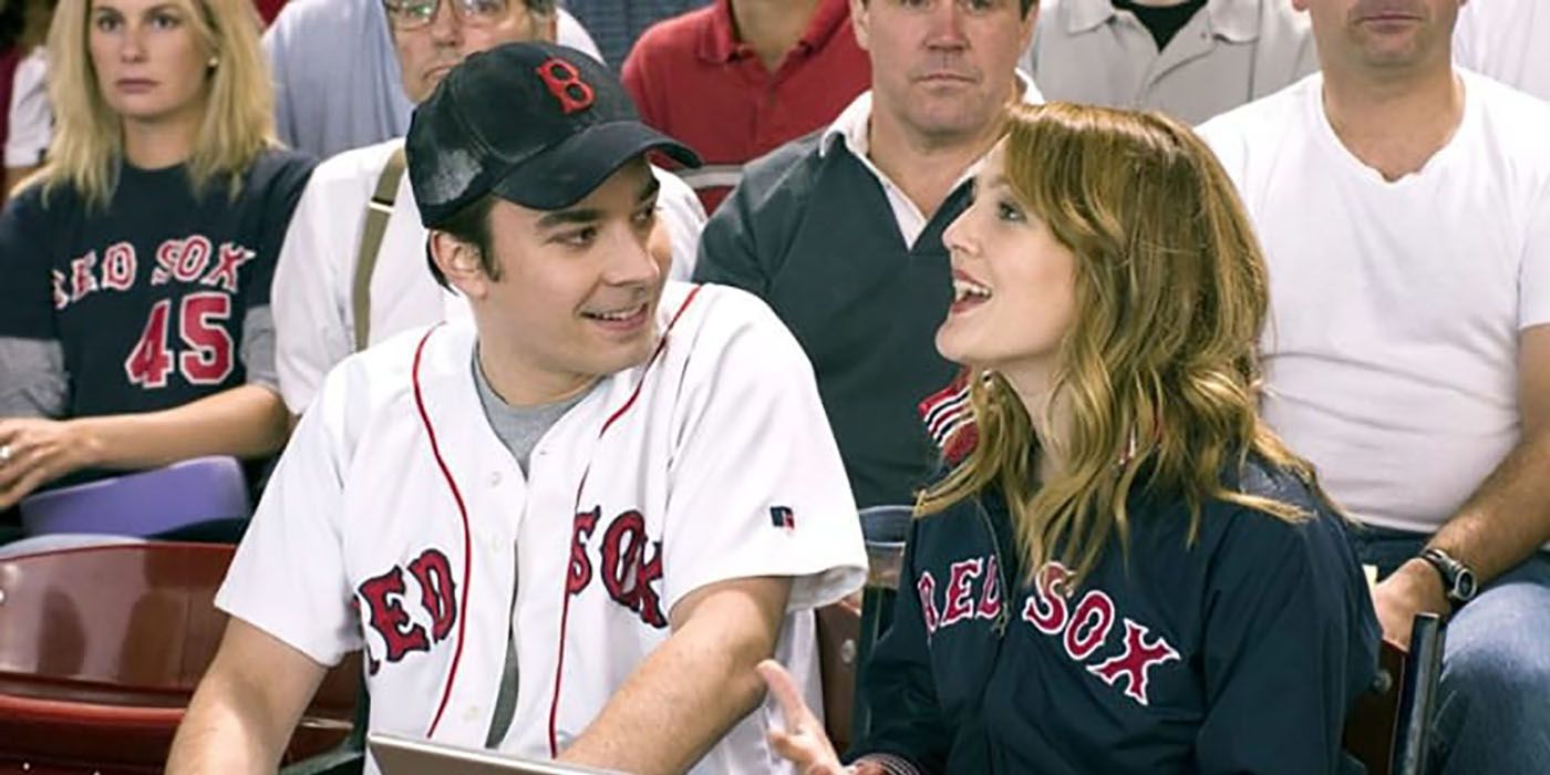 Jimmy Fallon e Drew Barrymore em Fever Pitch, sentados nas arquibancadas assistindo a um jogo de beisebol.