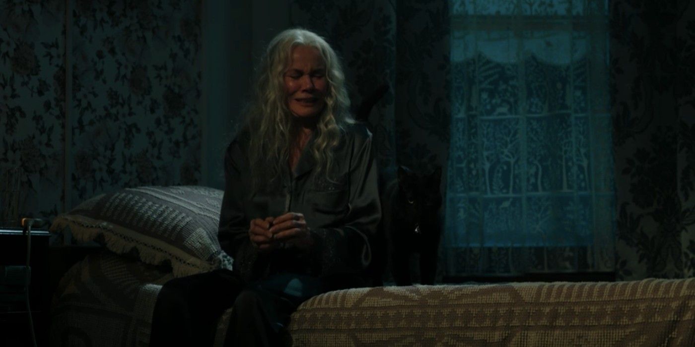 Judith is crying while looking at Ozzie the Cat on her bed in The Manor.
