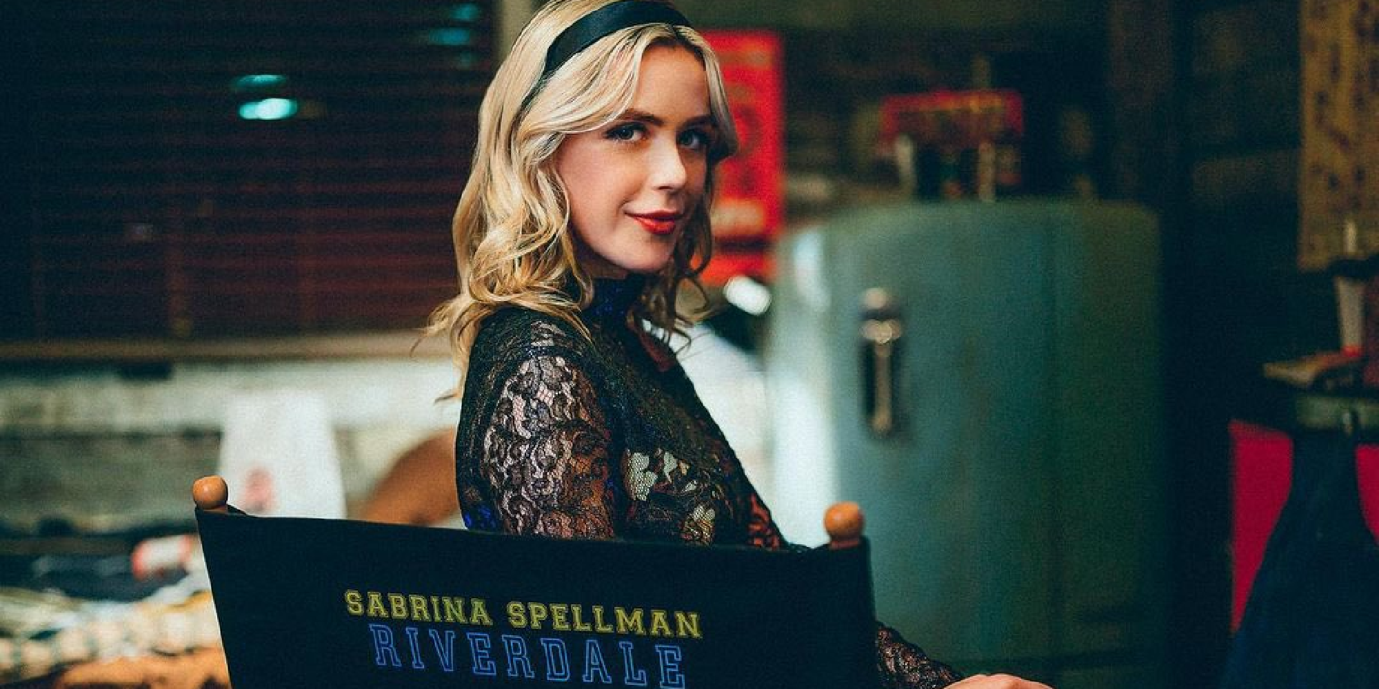 Sabrina sits on a chair with her name in Riverdale.