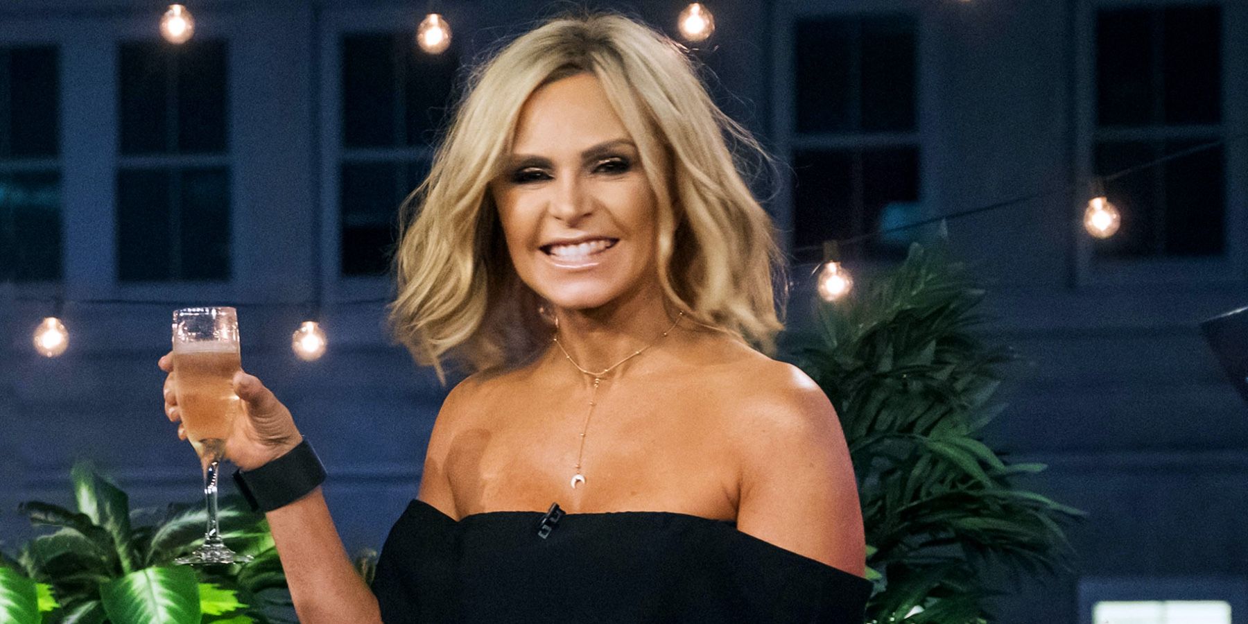 Tamra Judge holding a glass of champagne and smiling in RHOC