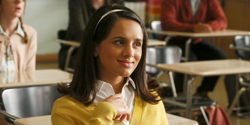 Sarika wears a yellow sweater at her desk in A.P. Bio