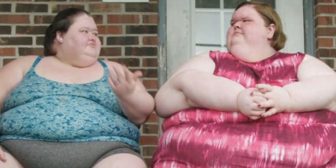 Amy Slaton and Tammy Slaton in 1000-lb Sisters sitting on touch wearing pink and blue