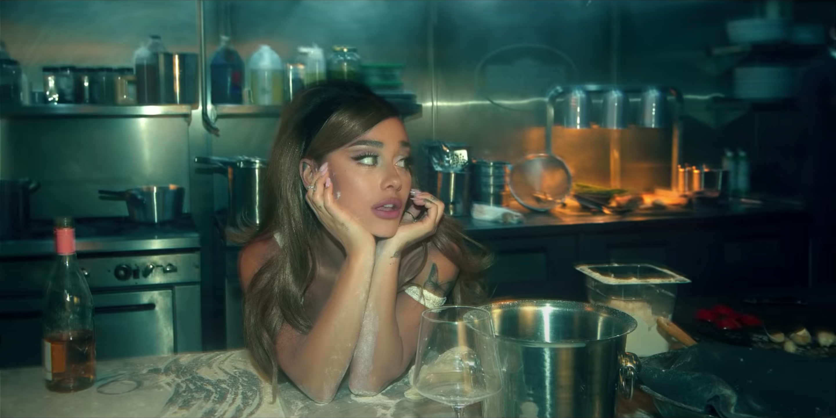 An image of Ariana Grande leaning onto a kitchen counter in the music video for Positions.