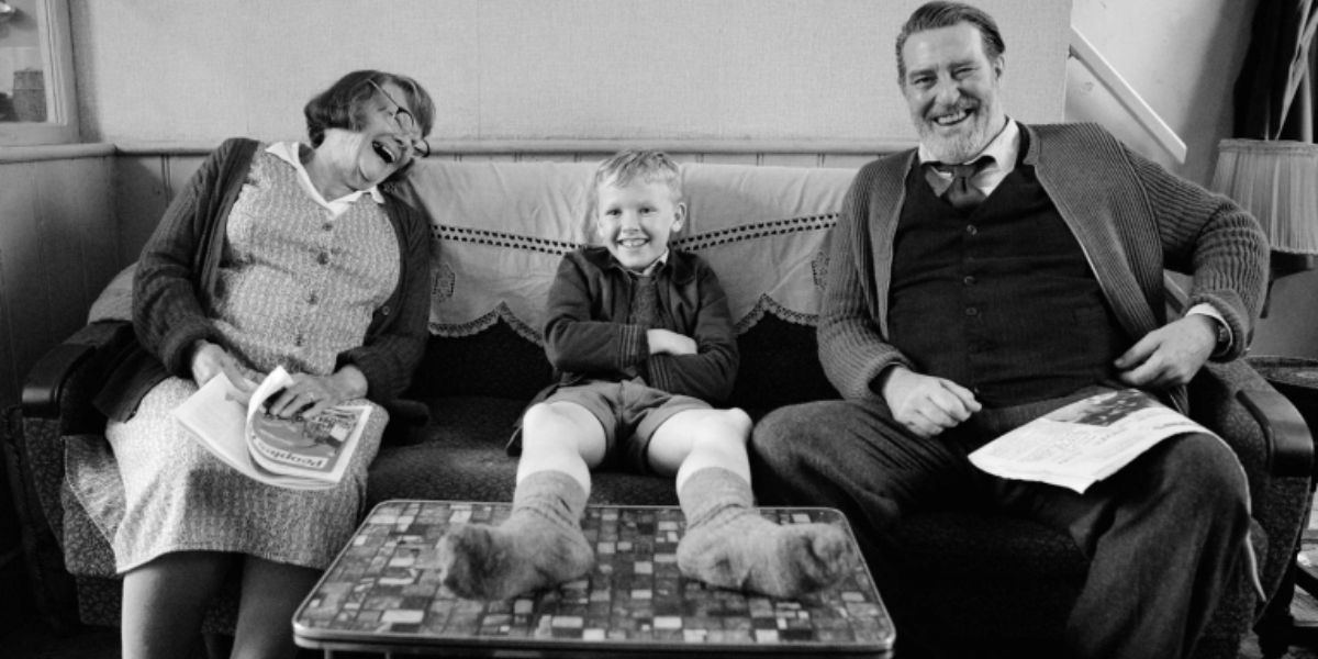 Granny, Pop, &amp; Buddy sits on a living room couch and laugh in Belfast.