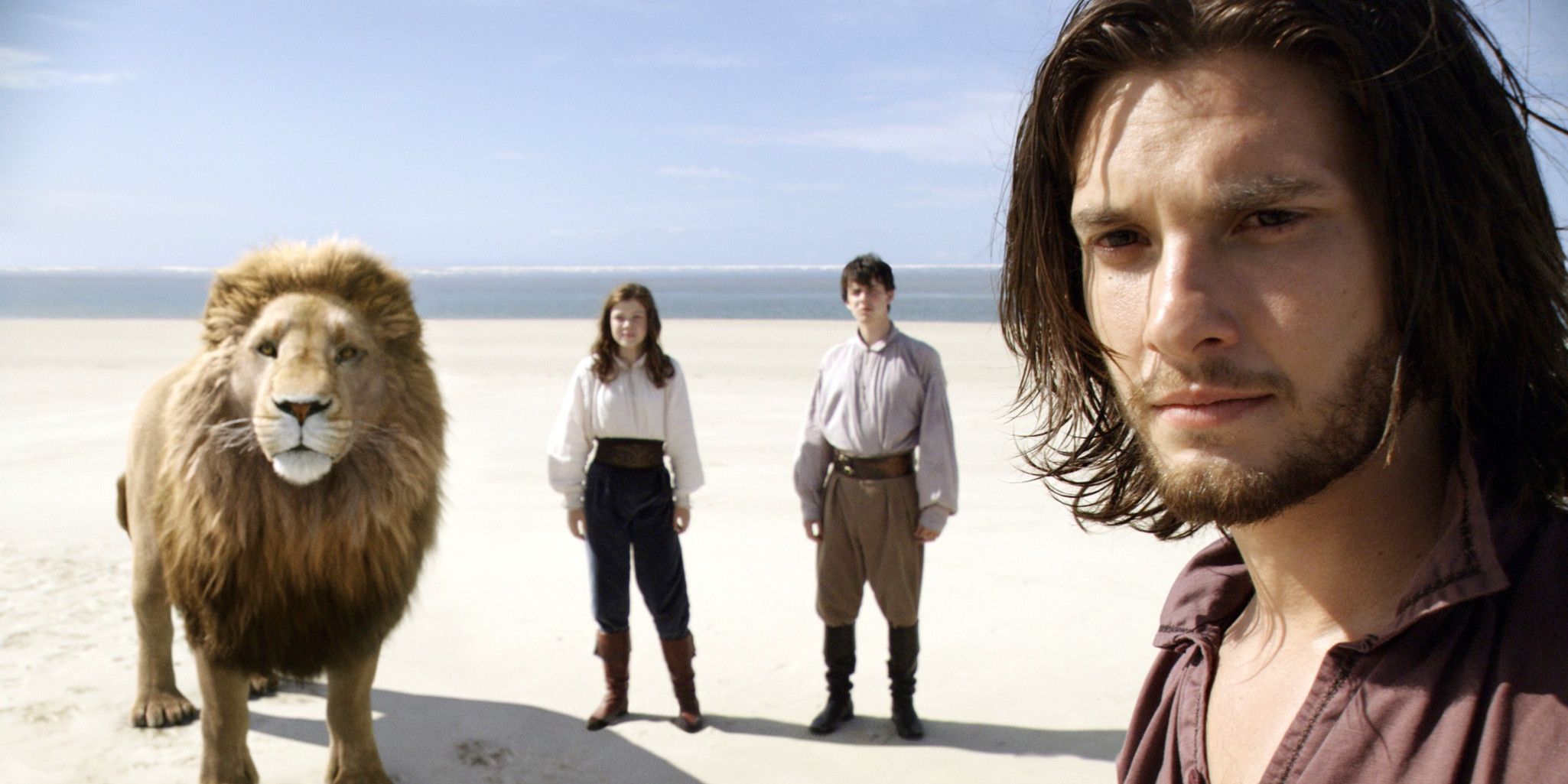 Prince Caspain stands with Aslan and 2 kids in The Chronicles of Narnia: The Voyage of the Dawn Treader