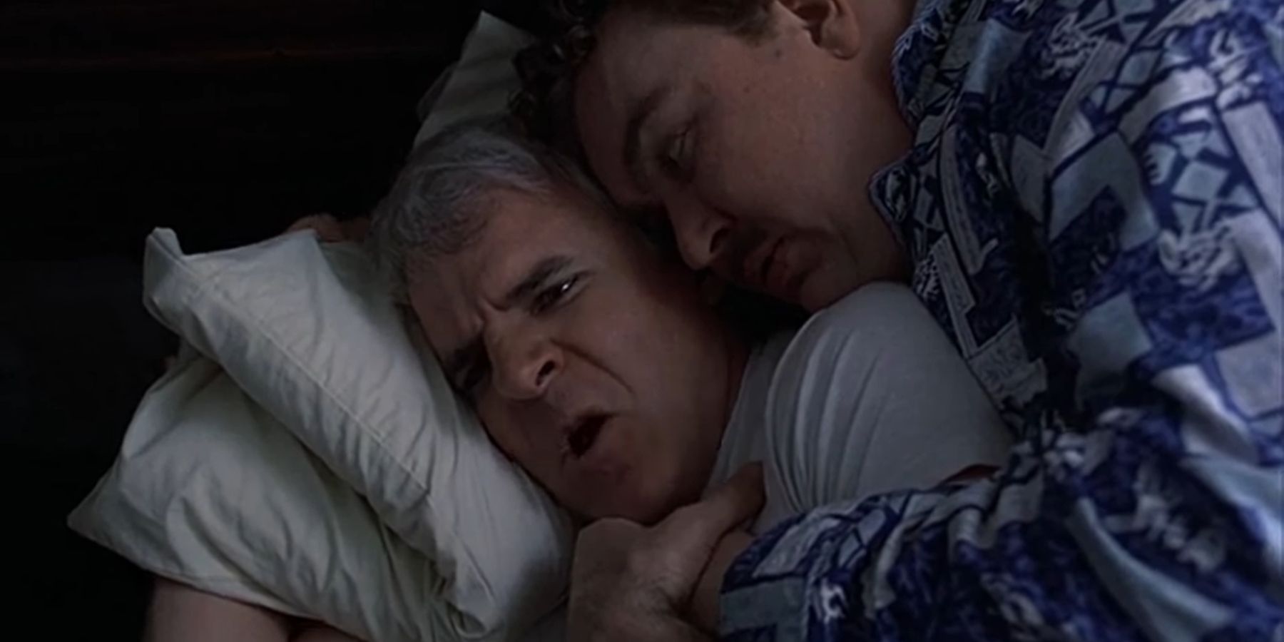 Del and Neal cuddling in bed in Planes Trains Automobiles