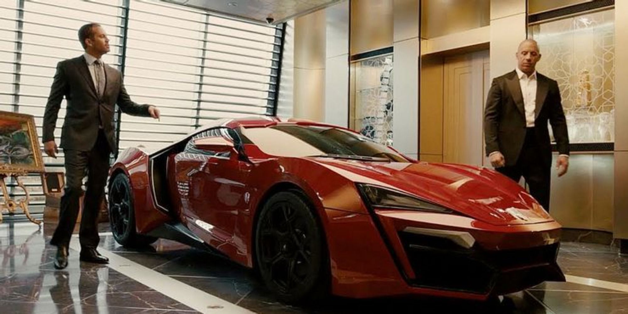 Dom and Brian standing next to a red supercar in Furious 7