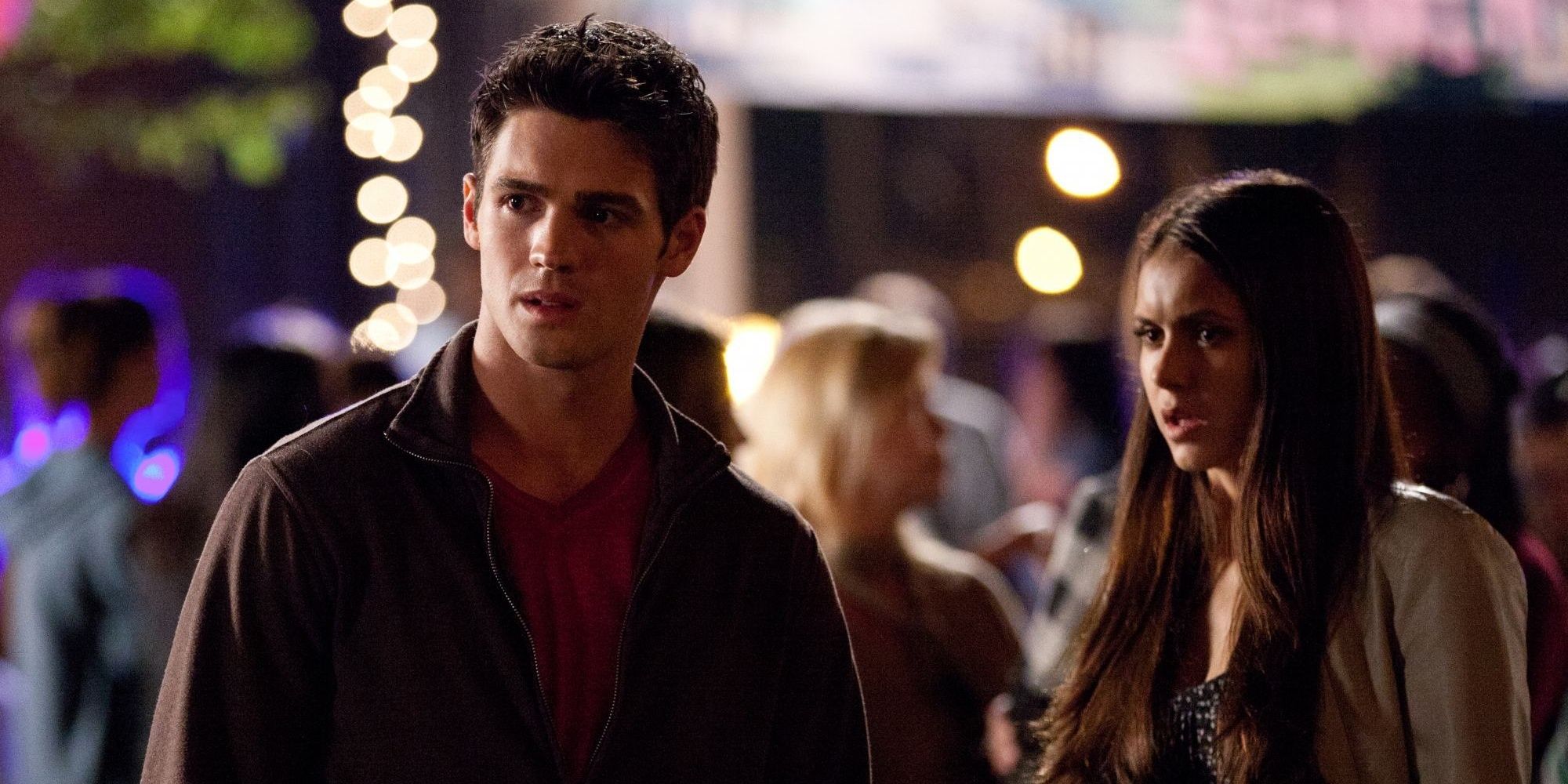Elena and her friend look bewildered in a crowd in The Vampire Diaries