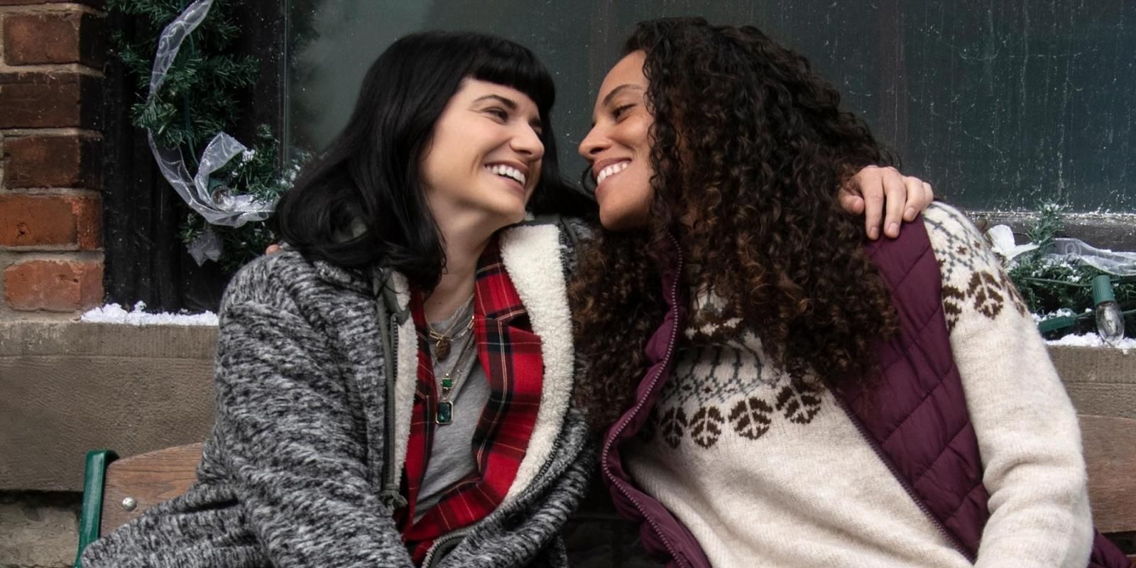 Elise Bauman and Tattiawna Jones embrace on a bench in Under the Christmas Tree