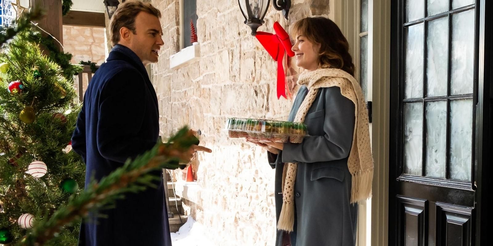 Erica Durance and Robin Dunne talk over a tray of cupcakes outside in The Enchanted Christmas Cake